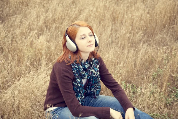 Lachende meisje met koptelefoon op veld. — Stockfoto