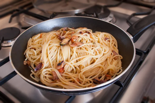 Spaghetti with clams into frying pan on stoves — Stock Photo, Image