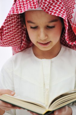 Muslim Arabic little boy reading Qoran clipart