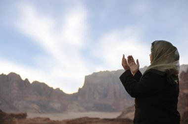 Silhouette of a muslim woman praying on the desert clipart