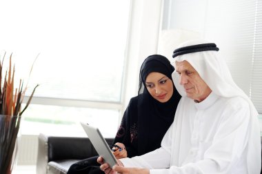 Two couple muslim lookig at tablet on office clipart