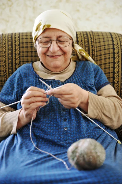 Image of an old arabic woman sitting on a sofa and knitting — Stock Photo, Image
