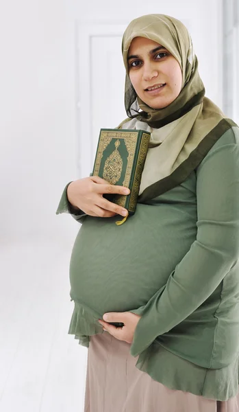 Muzułmańska kobieta w ciąży jest przytrzymanie ostrokrzew koran — Zdjęcie stockowe