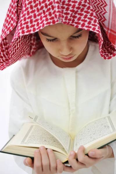 Muslim Arabic little boy reading Koran Stock Photo