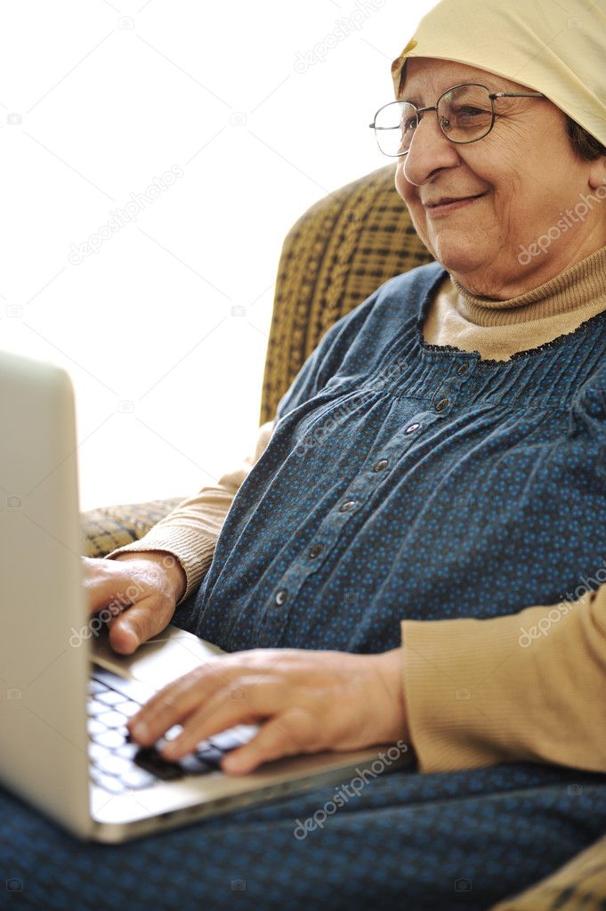 Elderly woman working on laptop in house