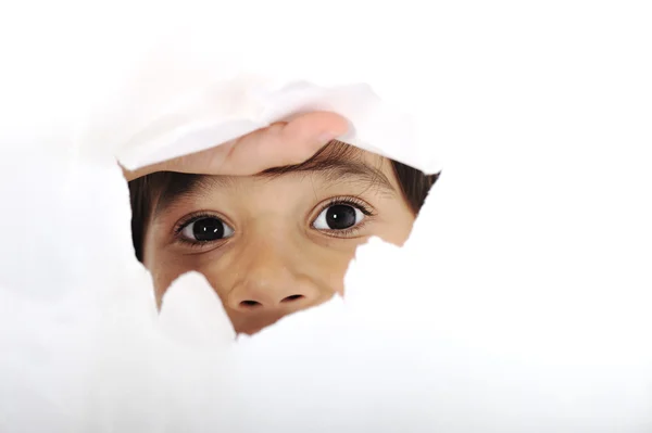 Хлопчик дивиться в отвір на аркуші паперу — стокове фото
