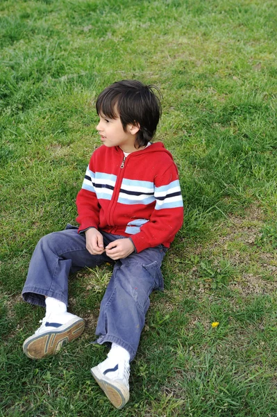Samotné dítě chlapec sedí v trávě — Stock fotografie