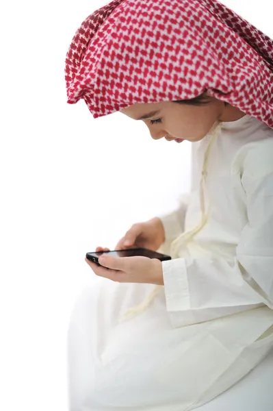 Παιδί με παραδοσιακό Μέσης Ανατολής ρούχα αναπαραγωγή πληκτρολογώντας μήνυμα στο κινητό — Φωτογραφία Αρχείου