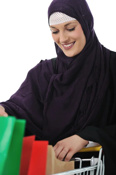 Mujer musulmana feliz con carrito de compras sobre blanco — Foto de Stock