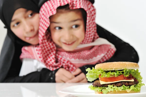 Arabská dívka a chlapec s big burger — Stock fotografie