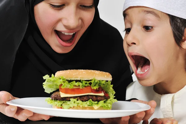 Árabe pouco masculino e feminino comer hambúrguer — Fotografia de Stock