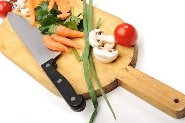 Vegetables cut by knife on wooden board in kitchen — Stock Photo, Image
