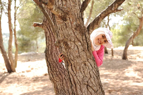 Arab muszlim lány, a természetben, bujkál behing a fa — Stock Fotó
