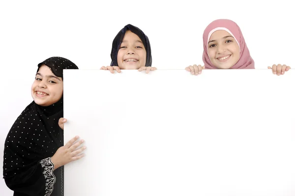 Três alunas a segurar um sinal branco para a tua mensagem. Bom para bordas de artigos ou sites. Belos modelos muçulmanos árabes. Isolado sobre fundo branco . — Fotografia de Stock