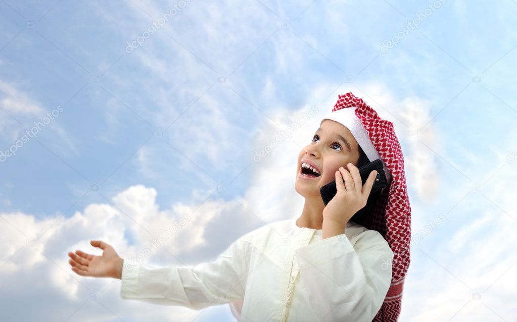 Arabic kid talking on phone outside