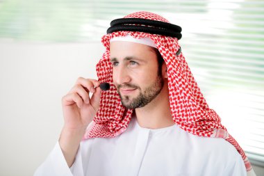 Portrait of a smart arabic business man using headset. Call cen clipart