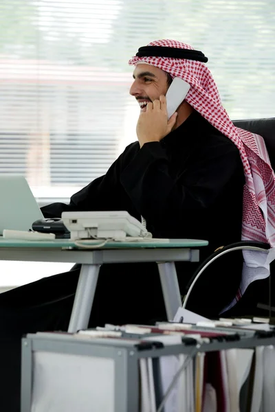 Portréja egy intelligens Arab üzleti ember használ laptop, és beszél a telefonon — Stock Fotó
