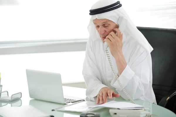Retrato de un hombre de negocios árabe inteligente usando el ordenador portátil y hablando por teléfono —  Fotos de Stock