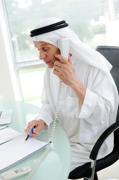 Dizüstü bilgisayar kullanan ve telefonda konuşurken bir akıllı Arapça iş adamı portresi — Stok fotoğraf