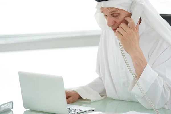 Ritratto di un uomo d'affari arabo intelligente che usa il computer portatile e parla al telefono — Foto Stock