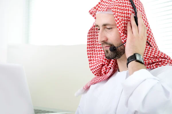 Portréja egy intelligens Arab üzleti ember használ a laptop és a fülhallgató. Call-center. ügyfélszolgálat. helpdesk. — Stock Fotó