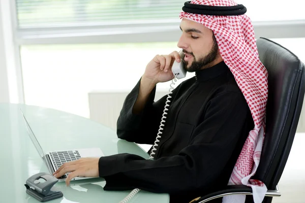 Portret van een slimme Arabische zakenman met behulp van laptop en praten over de telefoon — Stockfoto