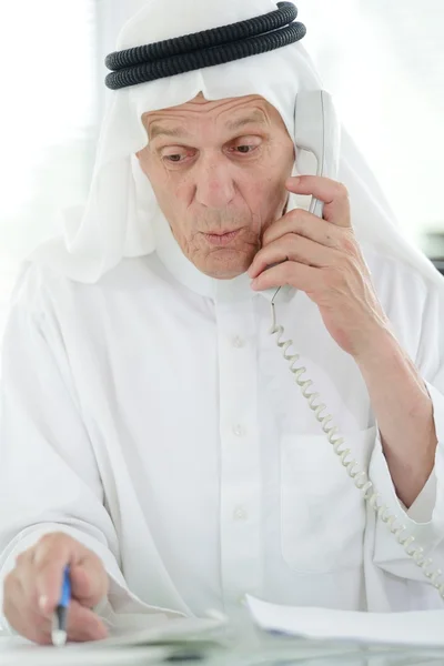 Portret van een slimme Arabische zakenman met behulp van laptop en praten over de telefoon — Stockfoto