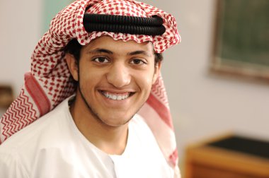 Smiling young success man, arabic clothes, education concept, indoor, school or university, student or teacher. clipart