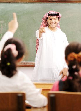 Arabic Muslim teacher in classroom with children. Competition an clipart