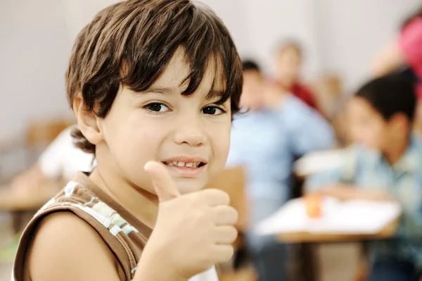 Happy boy in classroom with thumb up — Stock Photo, Image
