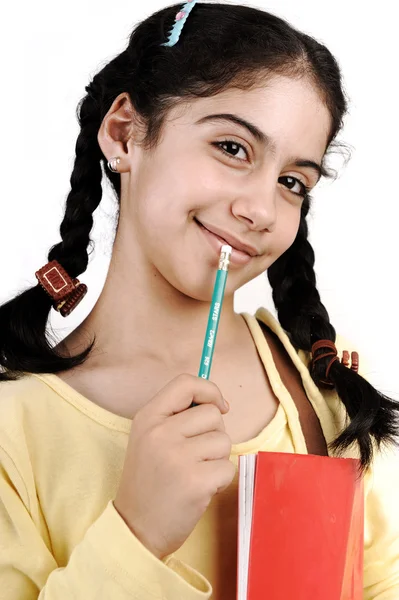 Aranyos iskoláslány gondolkodás, a kar és a ceruza :) elszigetelt szájban tartott notebook — Stock Fotó
