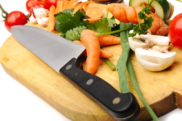 Légumes coupés au couteau sur planche en bois dans la cuisine — Photo