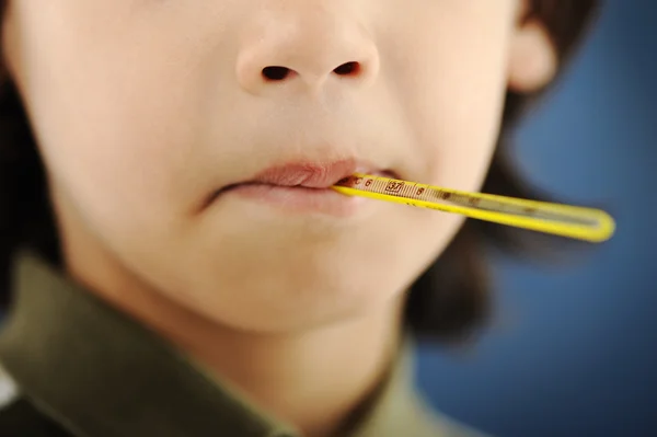 Больной мальчик с термометром во рту — стоковое фото