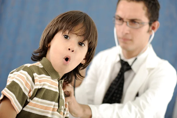 남성 의사 병원에 아이가 충격된 얼굴을 찡 그리기 함께 카메라를 보고 어린이 환자를 검사. — 스톡 사진