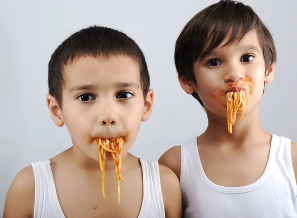Dos niños comiendo espaguetis — Foto de Stock