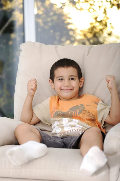 Criança feliz sentada no sofá — Fotografia de Stock