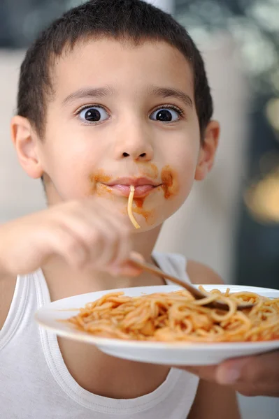Вкусная еда, грязный ребенок ест спагетти — стоковое фото