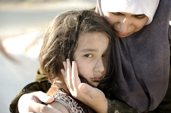 Armoede en poorness op het gezicht van de kinderen. triest meisje. vluchteling. in islamitische moeder armen. Stockafbeelding