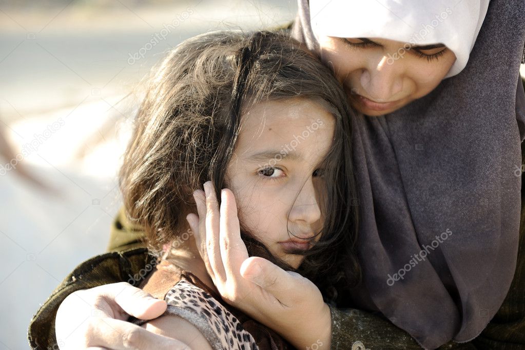 Poverty and poorness on the children face. Sad little girl. Refugee. In Muslim mother's arms.