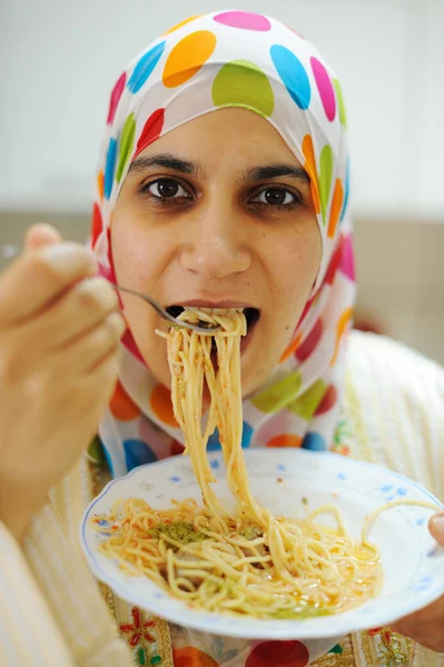 Молодая счастливая мусульманка с тарелкой спагетти на кухне — стоковое фото
