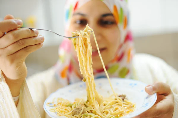 Unga glada muslimsk kvinna med tallrik spaghetti på kök — Stockfoto