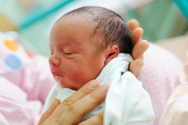 Mooie pasgeboren baby in zijn handen moeders. Stockfoto