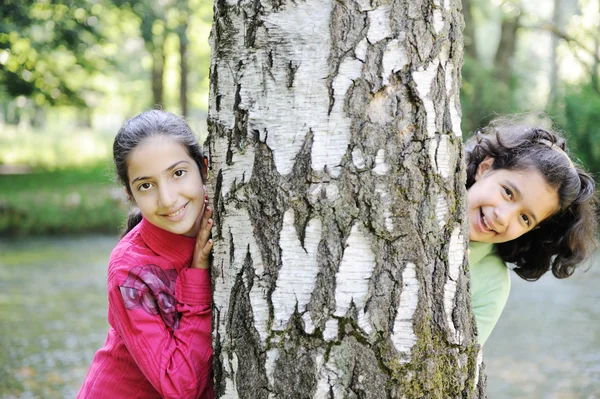 Two little arabic girls playing on the park tree outdoor — Stock Photo, Image