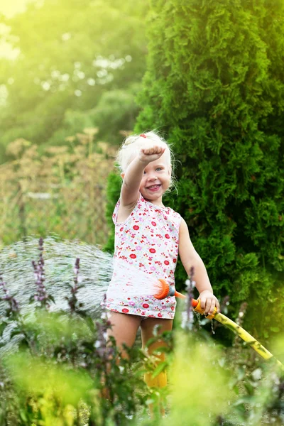 Bambina che annaffia l'erba in giardino — Foto Stock