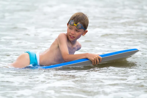 Niño pequeño con una tabla de bodyboard en la playa — Foto de Stock
