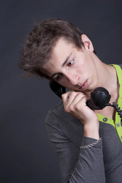 Ein trauriger junger Mann spricht mit einem alten Telefon — Stockfoto