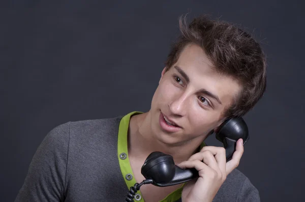 Fiatal srác beszél a régi telefont, és mosolyogva — Stock Fotó