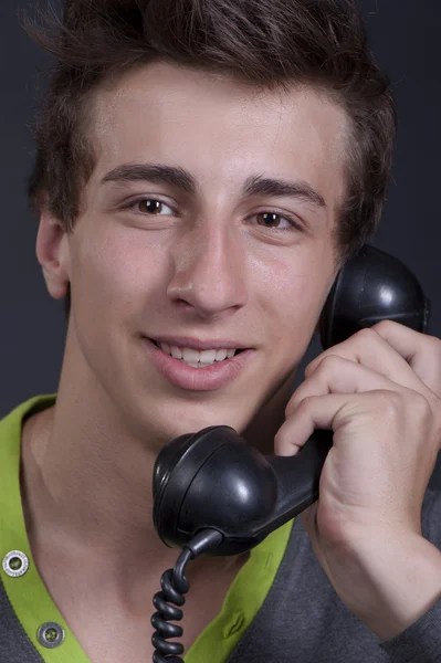 Chico joven hablando por el viejo teléfono y sonriendo — Foto de Stock