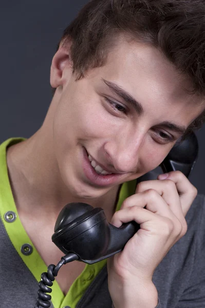 Ung kille talar i gamla telefon och ler — Stockfoto