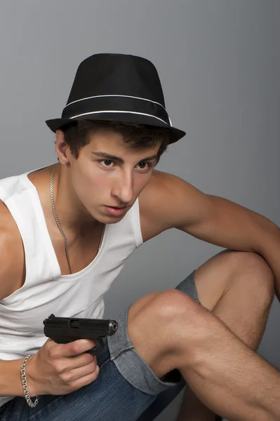 A young man with a gun in his hand — Stock Photo, Image